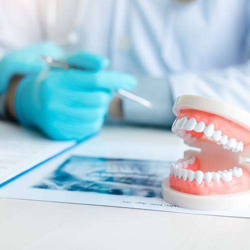 Man with white hair in dental chair smiling into mirror with dentist touching his teeth