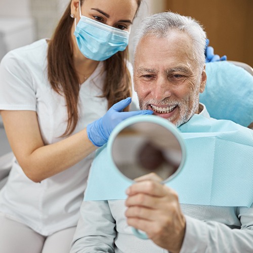 Dentist pointing to sample dental implant held by patient