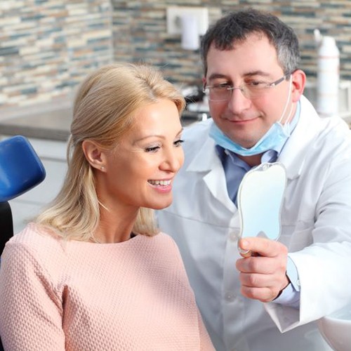 Dental patient admiring her smile after full mouth reconstruction